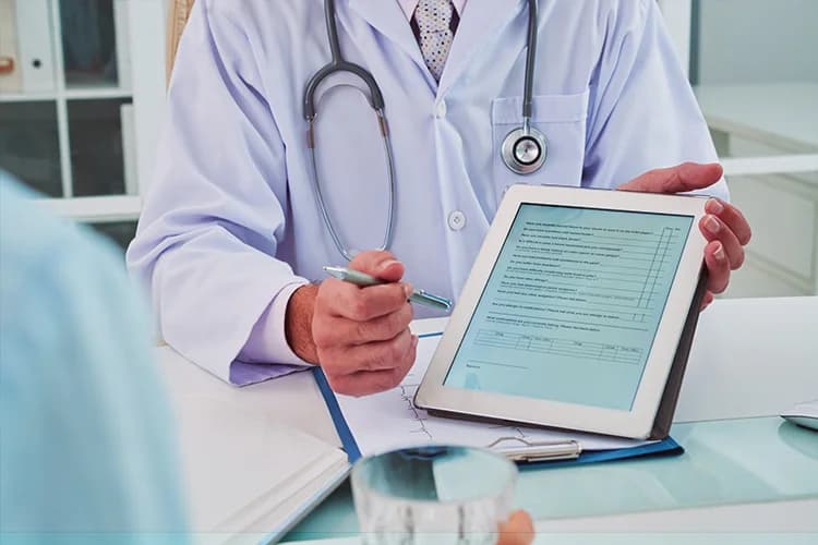Doctor showing patient records on tablet, representing ease of recording and retrieving cases with the best clinic management software.
