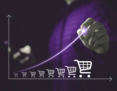 A hand drawing an upward growth curve over shopping cart icons, symbolizing how a business rule engine modernized a telecom operator’s legacy billing system with rule-based automation and faster offer launches.